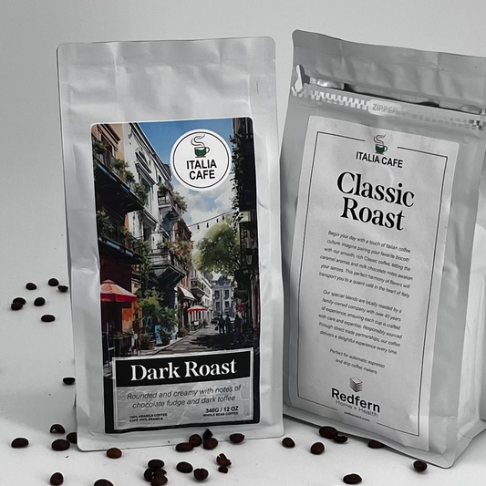Two bags of Italia Cafe coffee beans, one marked as Dark Roast and the other as Classic Roast, displayed with scattered coffee beans in the foreground.